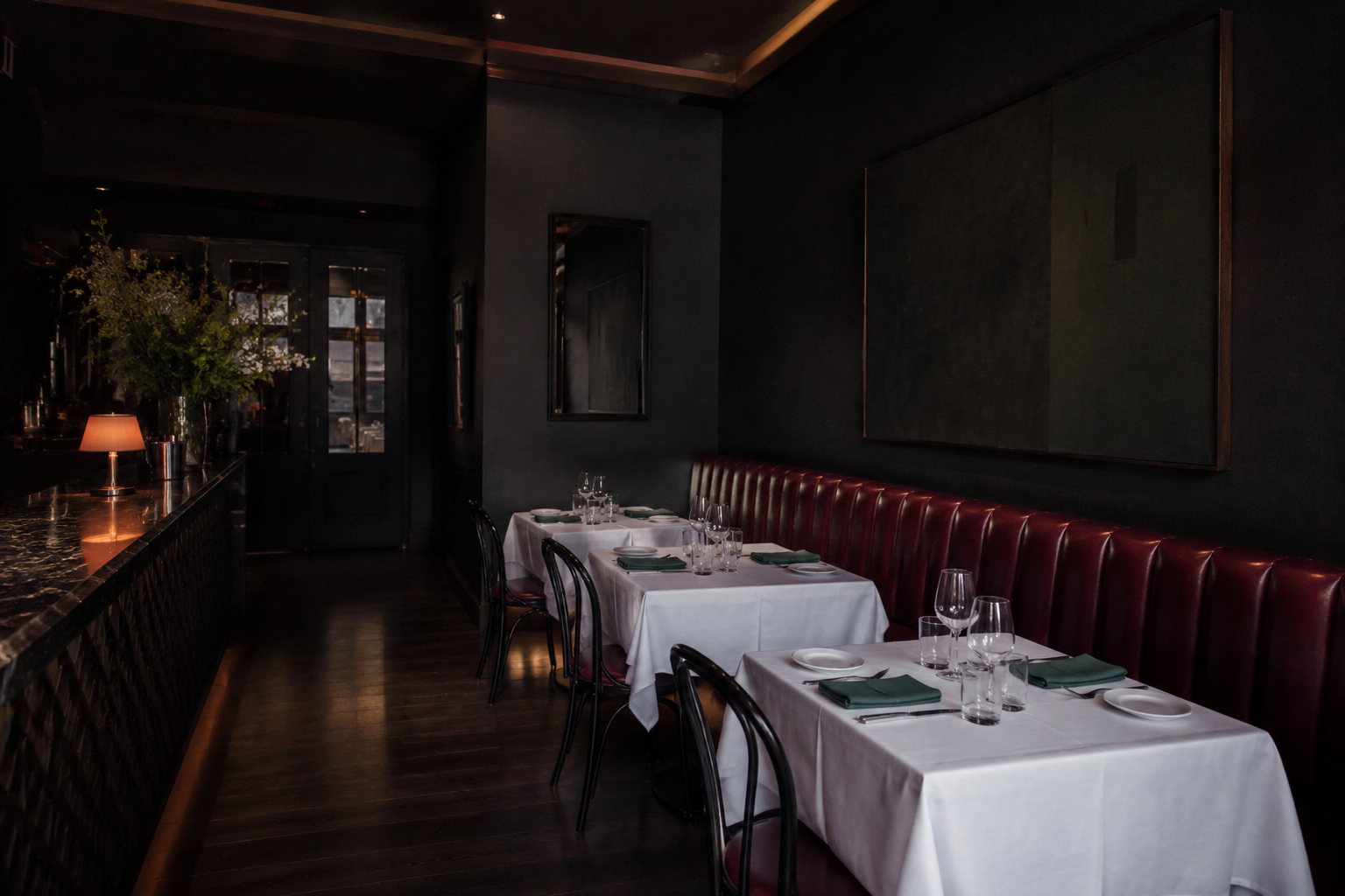 Ruhiger Restaurantsaal vor dem Abendservice, weiße Tischdecken und Bordeaux-Bänke